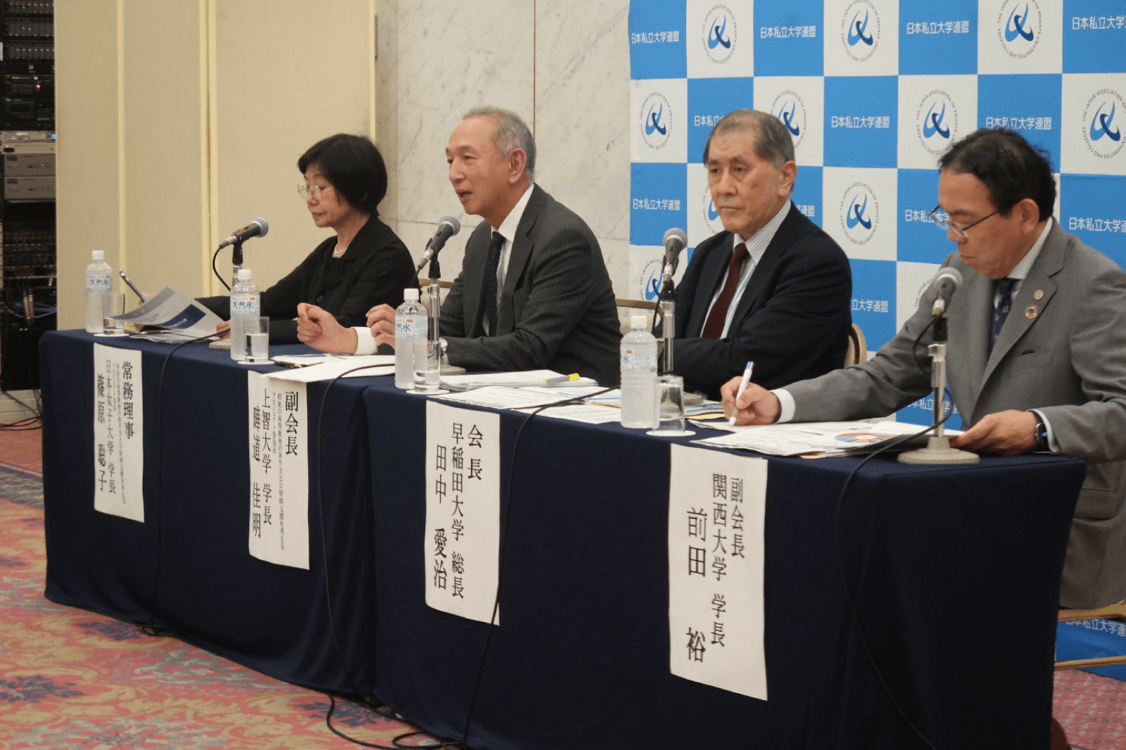 記者会見の会場で、私大連の役員4名が並んで着席し説明している様子。