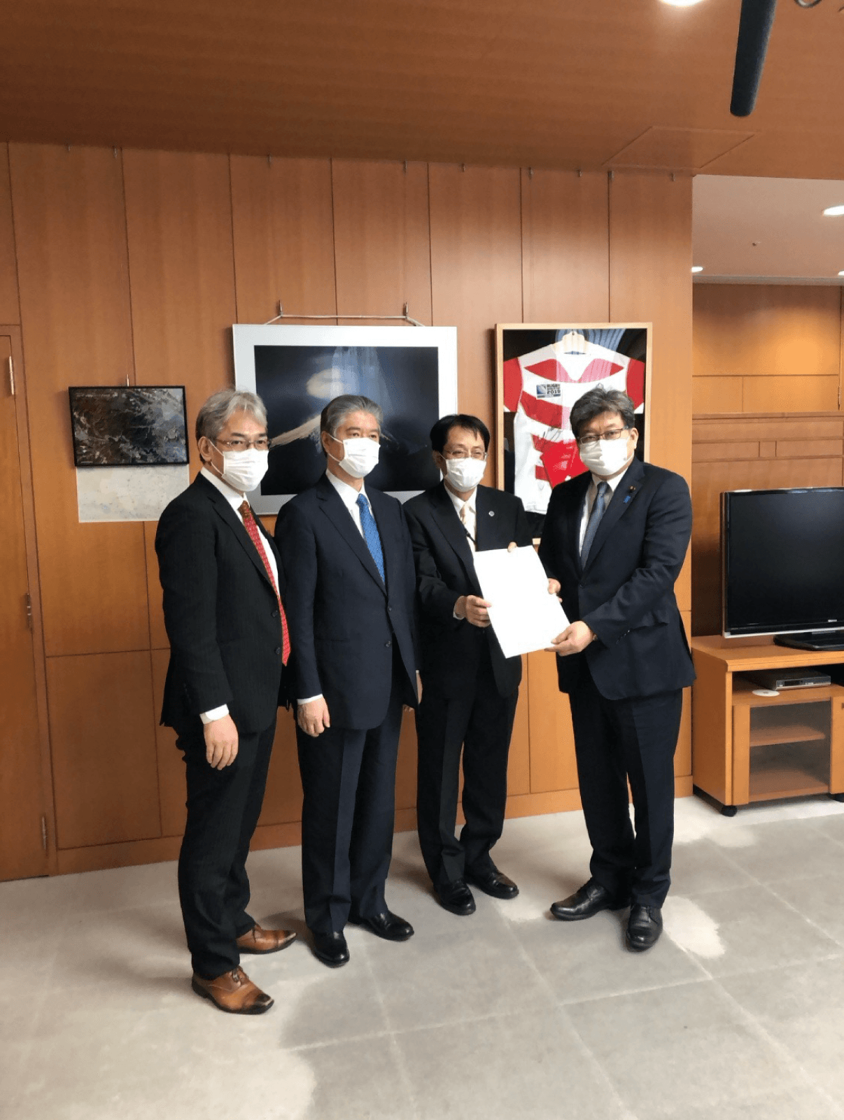 文部科学大臣室で、大学団体の代表者3名が文部科学大臣に要望書を手渡している様子。